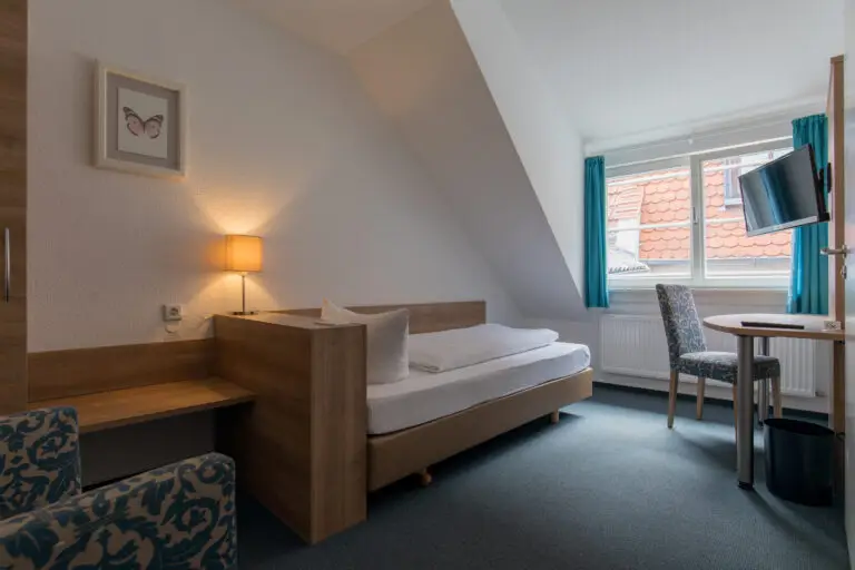 Standard single room with bed, desk and TV under the sloping roof