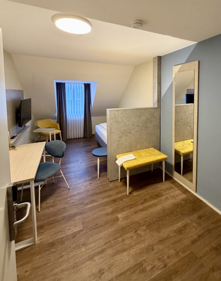 Single room with shared bathroom, desk and mirror under the sloping roof